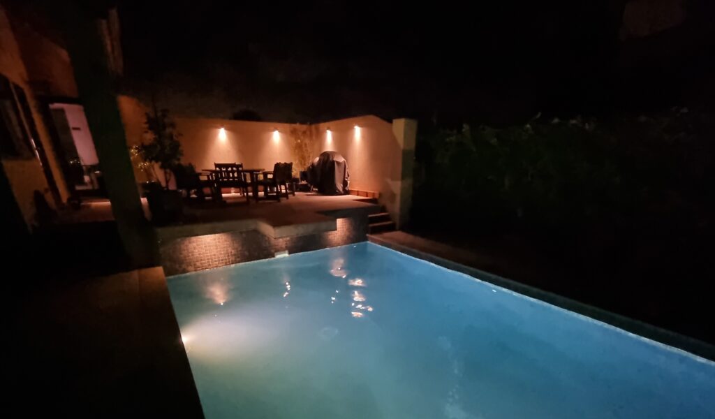 Castor Bay concrete pool at night with LED lighting on Ezarri glass tiles