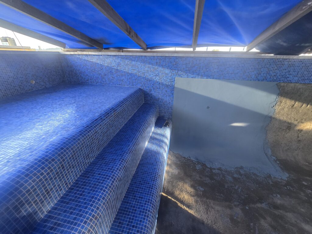 Renovated Coatsville pool with tiled sun shelf and stone coping, Auckland
