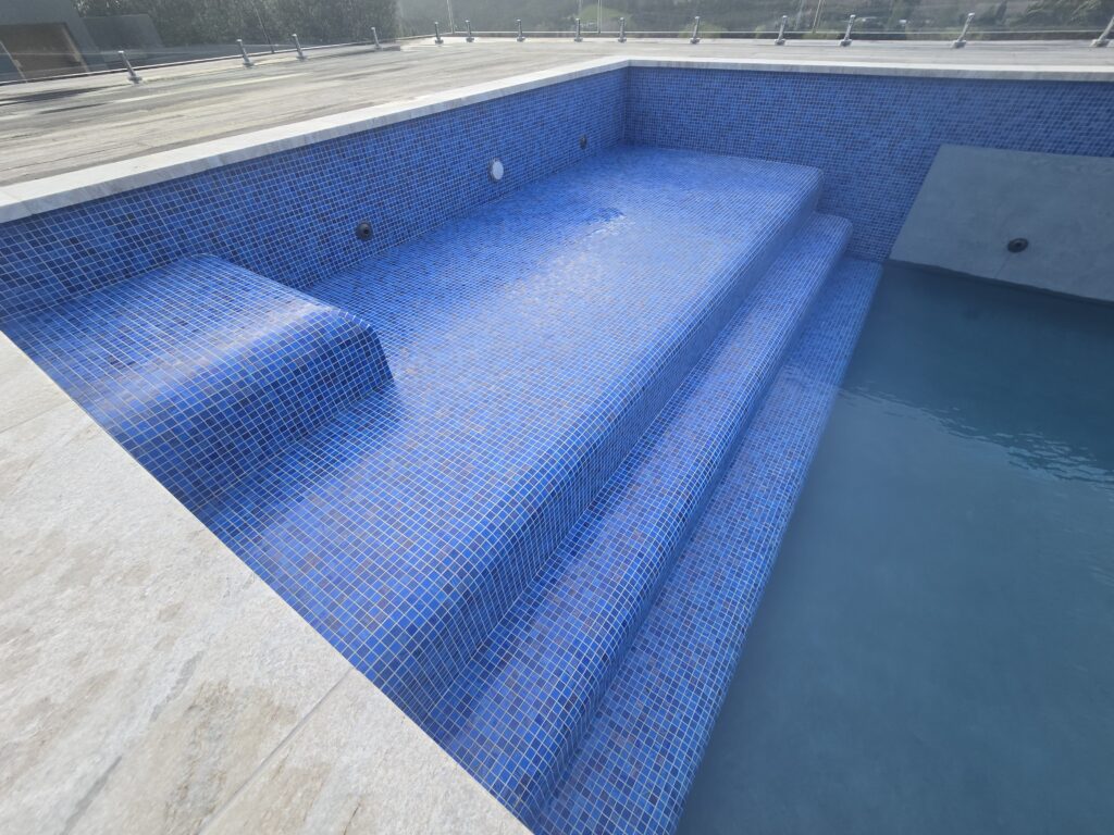 Blue glass mosaic steps in a finished concrete pool in Coatsville Auckland