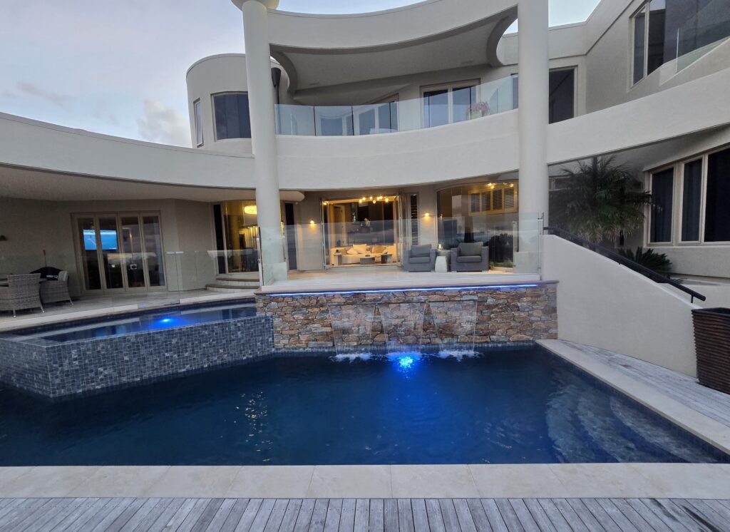 Completed concrete pool build in Waiake Auckland lit at dusk