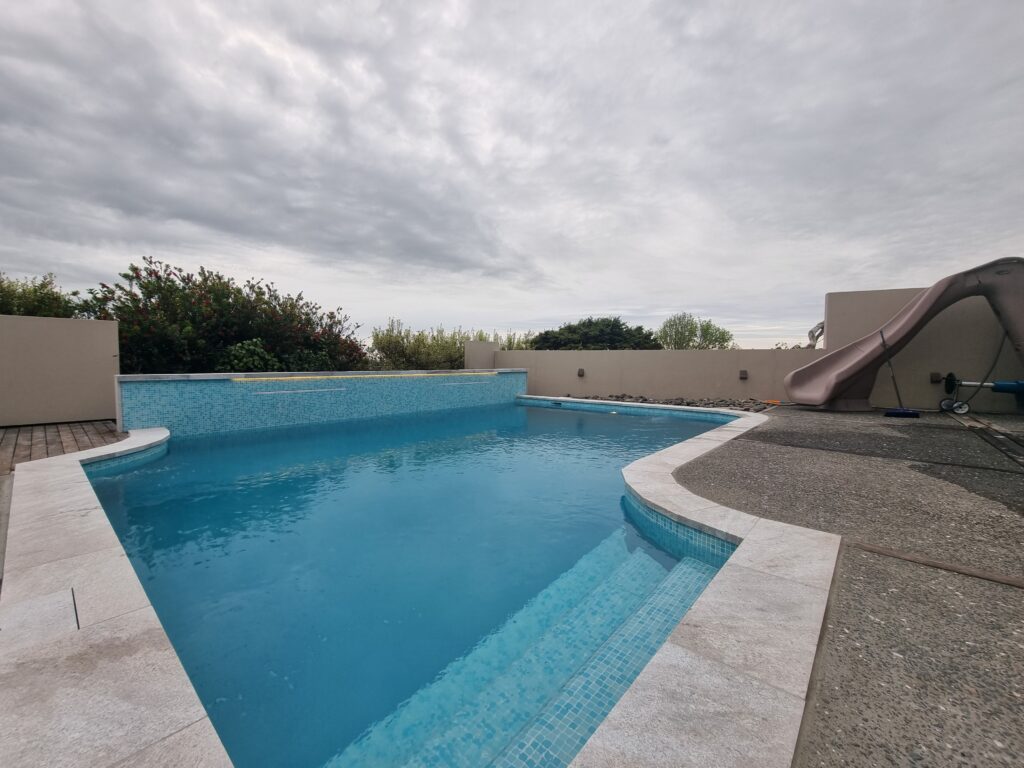 Finished concrete pool with slide and sun shelf in Howick Auckland
