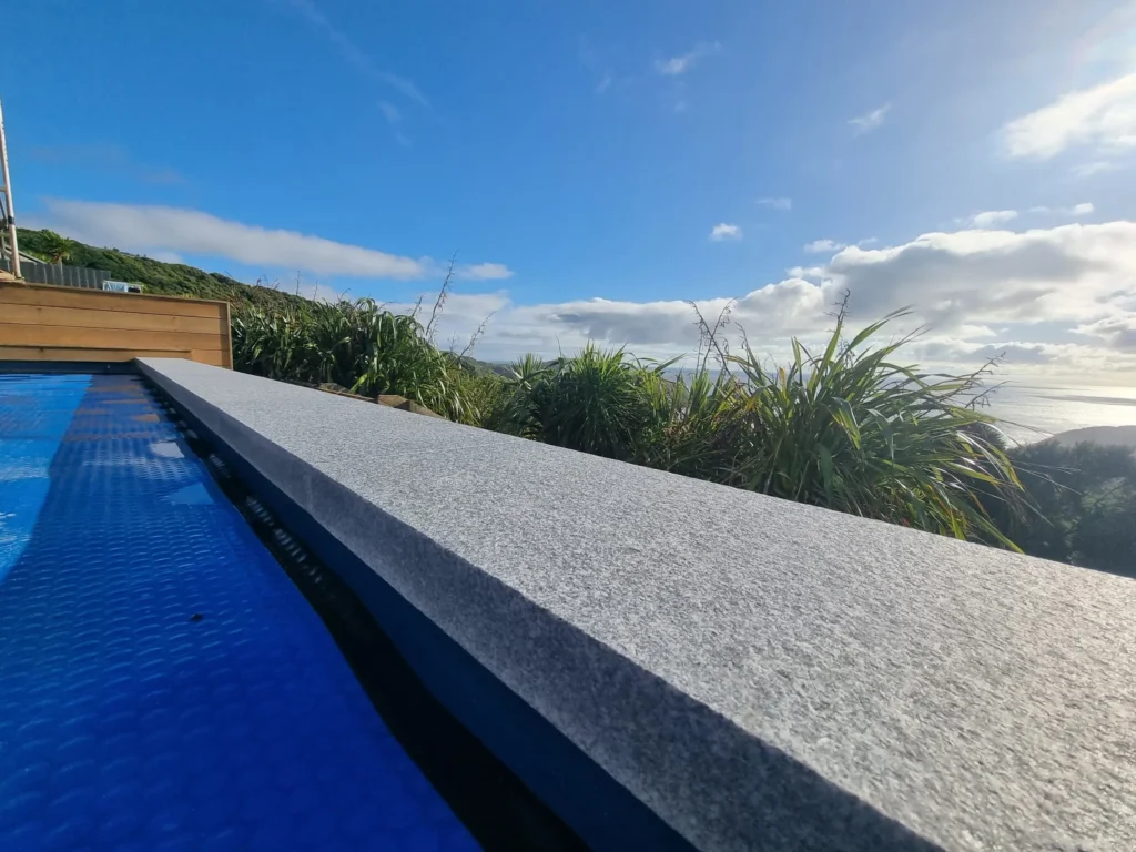 Wide grey stone pool coping with harbour views, Auckland